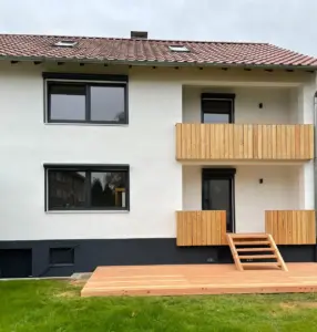 Außenansicht saniertes Wohnhaus – neuer Holzbalkon, Dachfenster und gedämmte Fassade, Referenzprojekt Artiscon Salzgitter